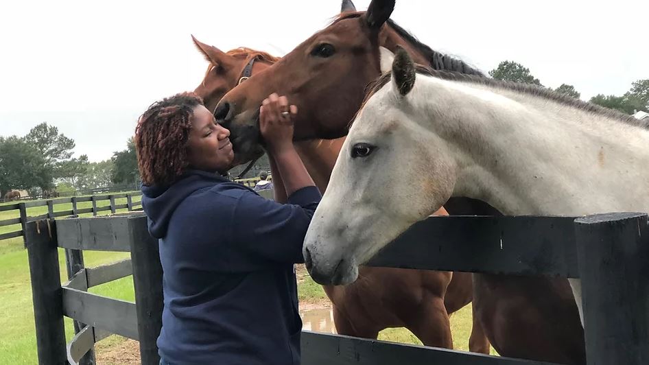 A woman petting horses at On Track Riding Academy